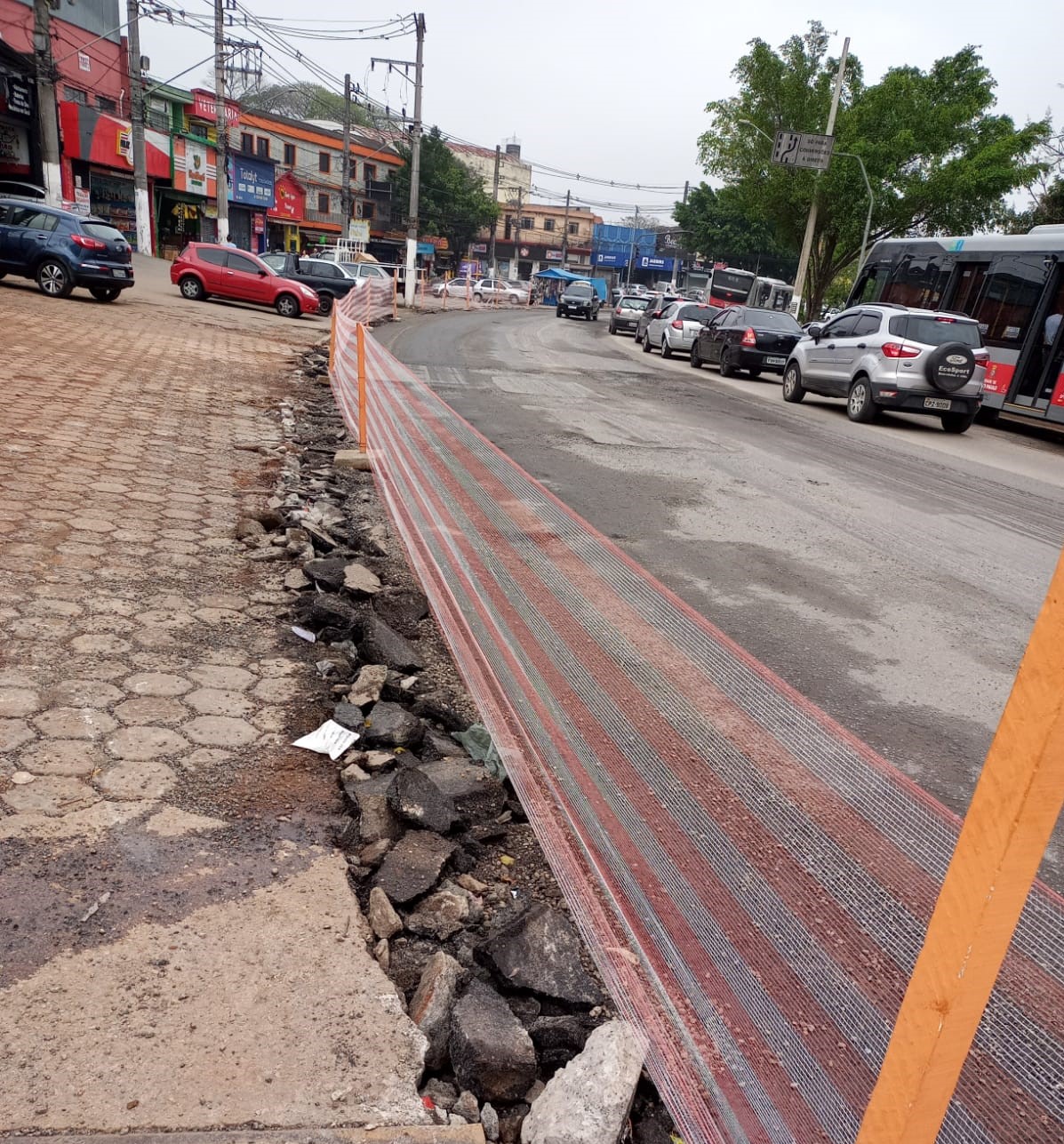 Asfalto raspado em uma avenida, com um ônibus transitando pelo local. 